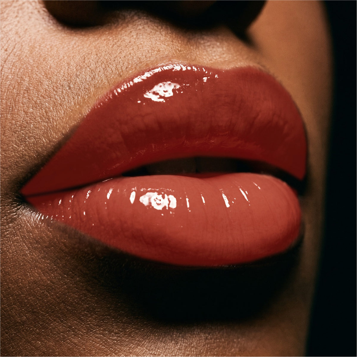 Close-up of glossy red lips wearing a shiny, high-shine lip gloss or lipstick.