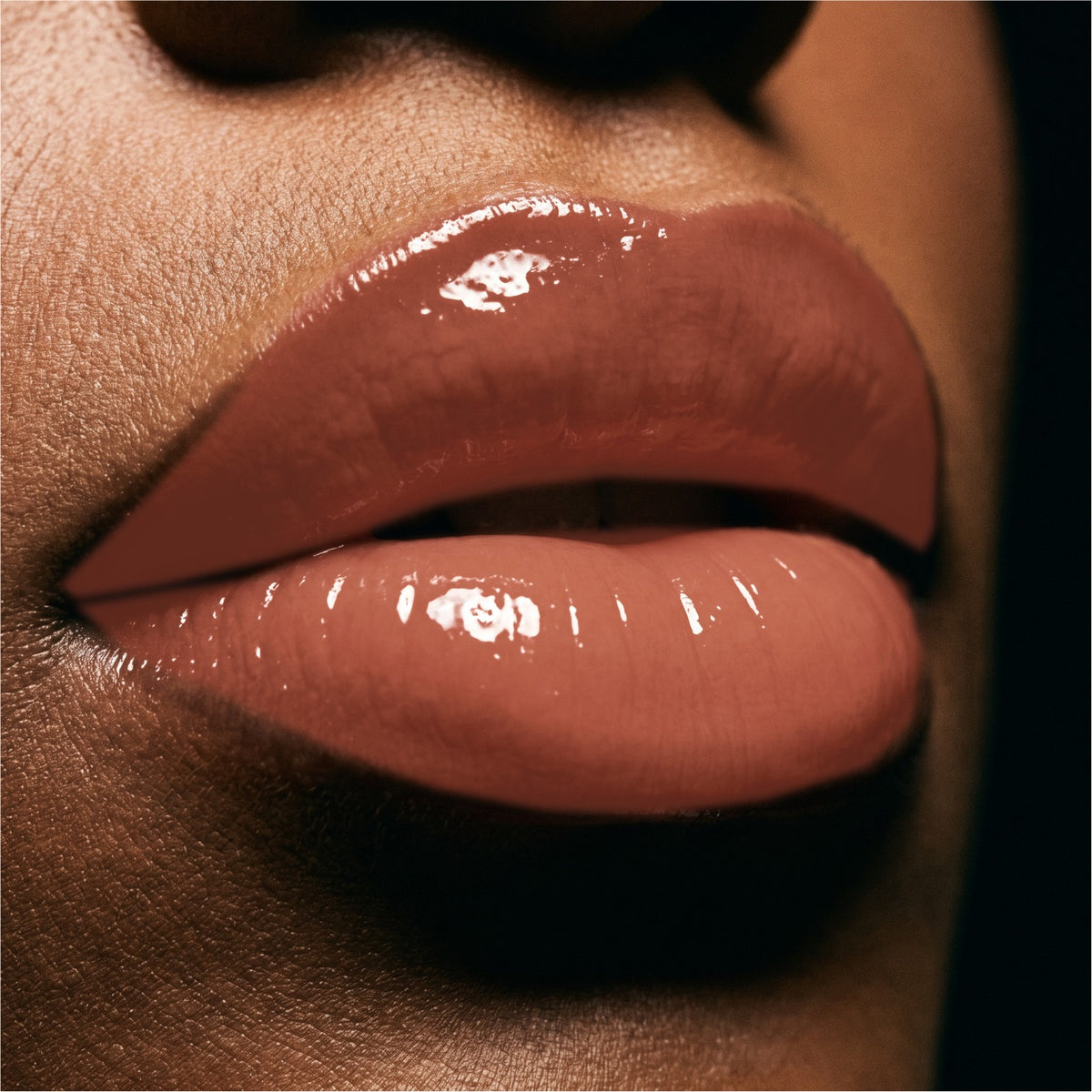Close-up of glossy Toffee  lips with a high-shine lip product on a model's face.